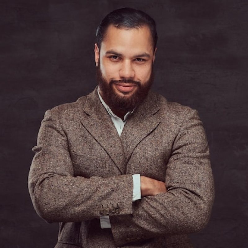 confident-african-american-businessman-brown-classic-jacket-with-crossing-arms-isolated-dark-background_613910-6555